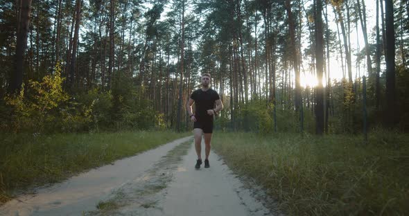 Young Active Guy Running on Road Among Summer Forest