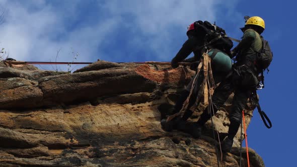Man and woman rappelling at sandstone cliff edge (Caatinga, Brazil)