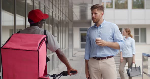 African Delivery Man Asking Caucasian Businessman for Direction Outside Business Center