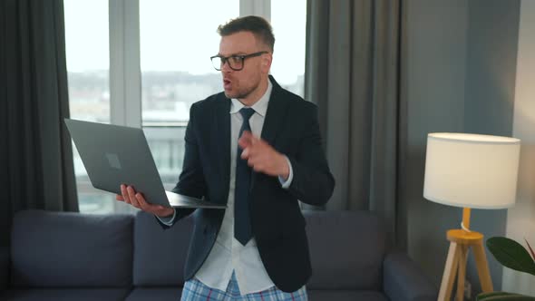 Caucasian Man Dressed in a Jacket and Underwear Using Laptop to Make a Video Call From Home in a