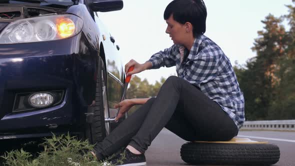 Female Changing a Tire Outdoors