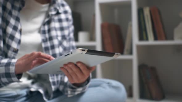 Girl Student Sits On The Floor With A Tablet In Her Hands. Tablet In Hands Closeup Student Concept