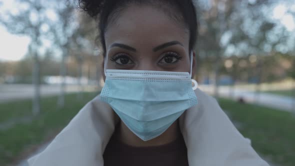 Portrait of Happy Young Hispanic Woman Removing Protective Face Mask Outdoors