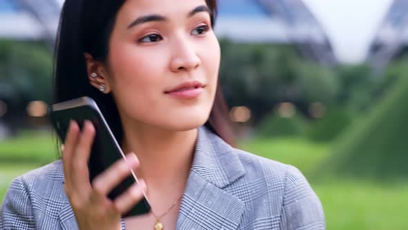 young asian woman is looking down at her mobile phone happily