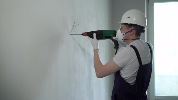 A Worker Builder on a Construction Site with a Punch Makes Repairs to an Apartment or a House