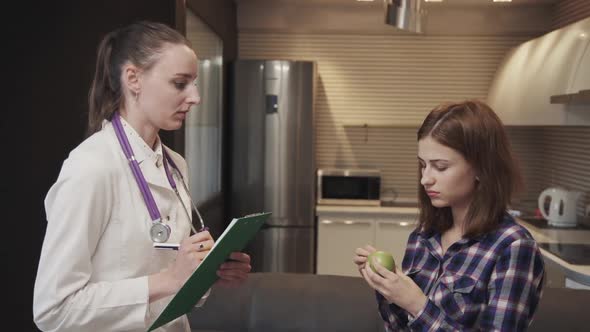 Woman Doctor Talking with Female Patient About Symptoms of Disease, Standing in Apartment.