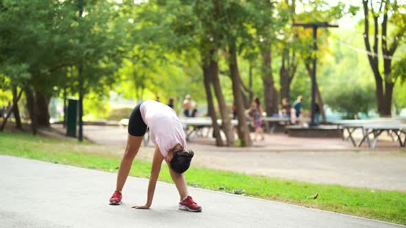 Fit woman doing exercises before jogging in park