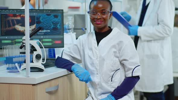 Black Doctor Woman Smiling at Camera Sitting in Scientific Lab