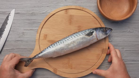 Top View of the Male Hands Putting the Round Wooden Board with the Mackerel Fish