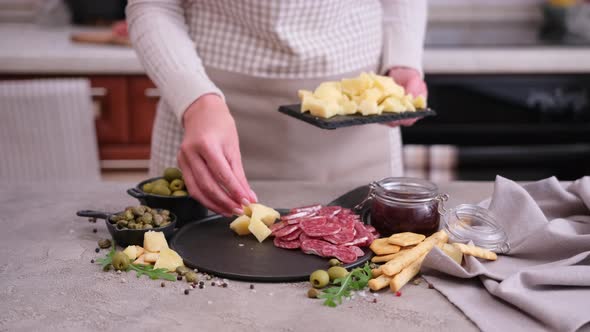 Making Meat and Cheese Antipasto Plater Woman Putting Pieces of Parmesan Hard Cheese on Stone