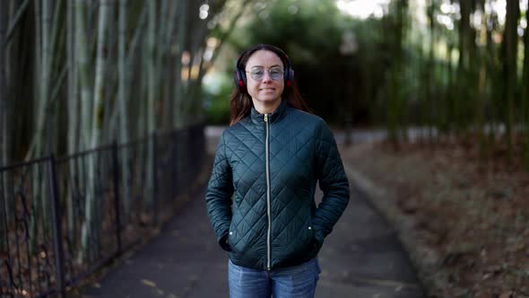 Happy Middleaged Woman is Listening to Song By Wireless Headphones and Dancing in Park