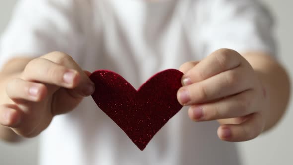 Red heart close up in hands of little kid boy on Valentines Day.