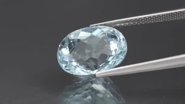 Natural Aquamarine in the Tweezers on the Background