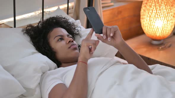 Smartphone Use By African Woman Laying in Bed