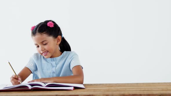 Smiling schoolgirl doing her homework