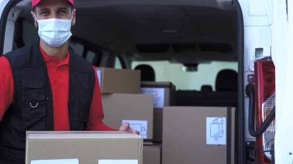 Delivery man loading boxes in the truck while wearing face mask to avoid corona virus spread