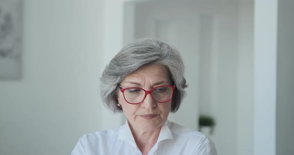 Strong Senior Mature Old Businesswoman Wearing Glasses Looks Seriously at the Camera