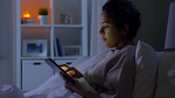Woman with Tablet Pc in Bed at Home at Night