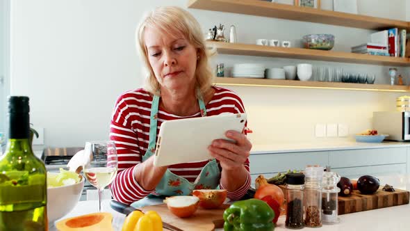 Woman using digital tablet while having a glass of wine