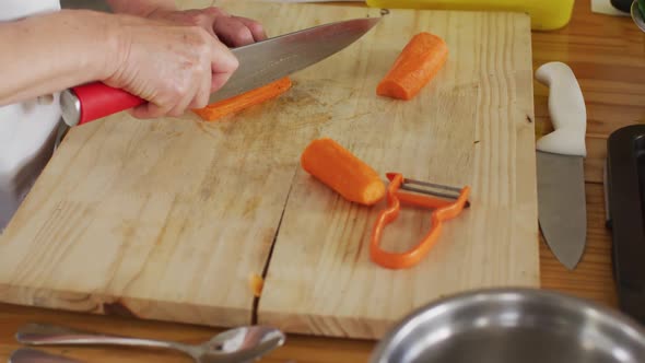 Caucasian female chef cutting carrots in kitchen