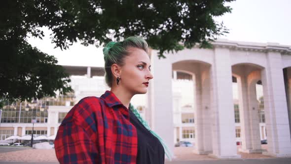 Portrait of Young Funky Woman with Mint Hair Color Smiling in Park Slow Motion