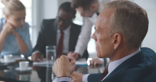 Close Up of Mature Businessman Sitting at Table and Talking with Employee at Corporate Meeting