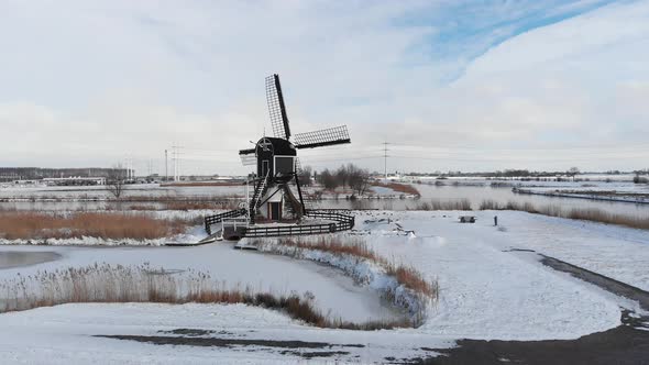 Winter snowstorm weather on Dutch windmills and canals, aerial view