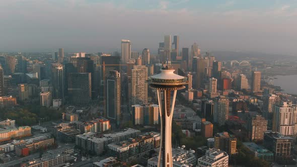 Aerial shot pushing in on the Space Needle during sunset with Seattle's downtown in the background.