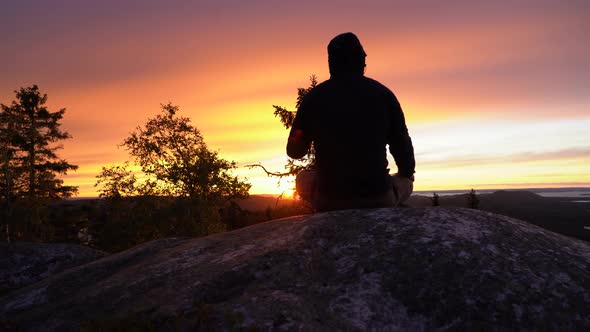 Slider shot of a male hiker sitting on a nordic mountain hill looking towards horizon and enjoying a