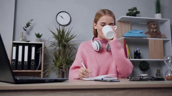 Attractive Modern Girl in Pink Sweater which Drinking Tea