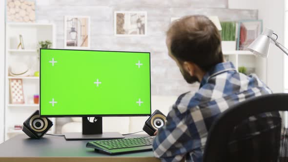 Static Shot of Man in Bright Living Room Working on Green Screen PC