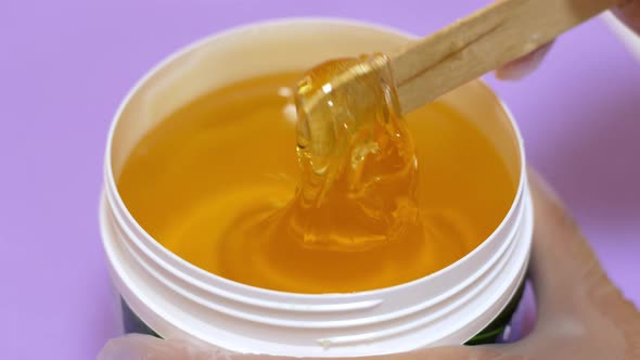 Sugar paste or honey wax for hair removal, dripping from wooden wax sticks - depilation and beauty.