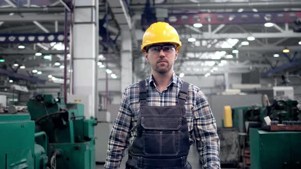 Engineer in Hard Hat is Moving Through a Heavy Industry Factory with a Tablet Computer