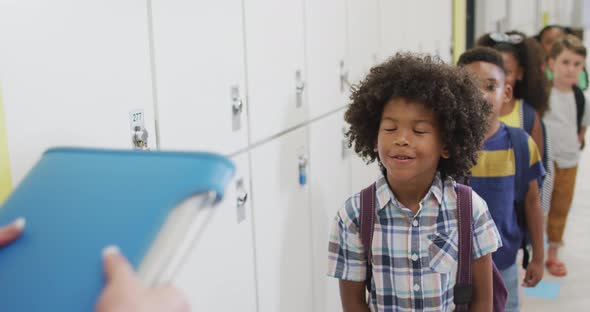 Video of happy african american pupil smiling to caucasian female teacher before lessons