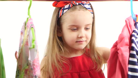 Little Girl at the Store Chooses Clothes and Finds Suitable. White Background