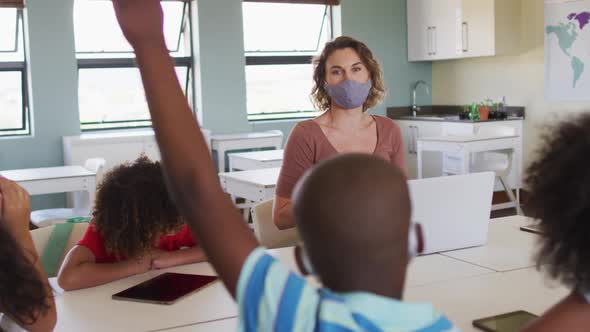 Female teacher wearing face mask teaching kids in the class at school