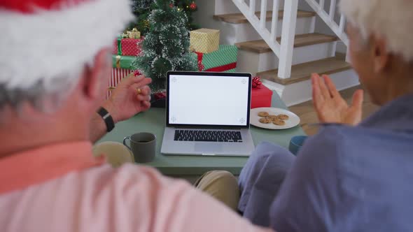 Animation of back view of caucasian senior couple using laptop with copy space at christmas time