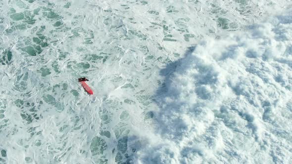 Rolling Ocean Wave Covers Surfing Person on Red Surfboard