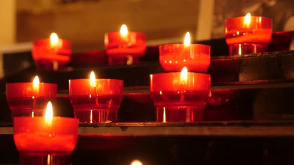 Shiny lit of Catholic prayer red cup votive candles in candle rack 4K 2160p 30fps UltraHD footage - 