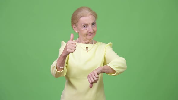 Senior Businesswoman Choosing Between Thumbs Up and Thumbs Down