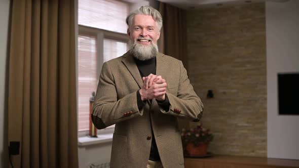 Adult gray-haired man with beard smiles and demonstrates cordiality