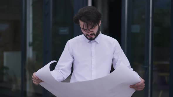 Confident Thoughtful Handsome Man Walking in Slow Motion with Paperwork on Office Terrace Analyzing