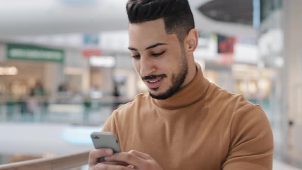 Closeup Young Arab Guy Walks Around Mall Holding Phone Chatting with Friends in Internet Reads Email