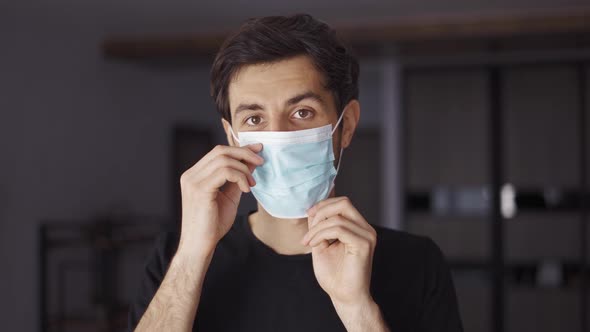 Dark Haired Man in Front Camera Put on a Mask Indoors