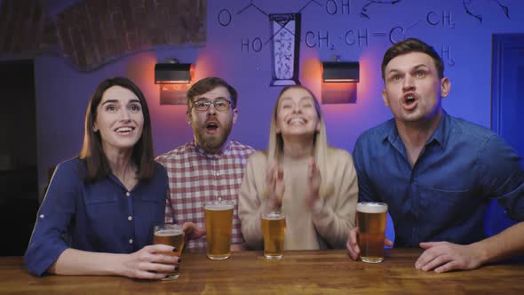 Friends in Pub Drink Beer on Bar Counter Watch Sport Game on Tv and Celebrate Goal of the Team