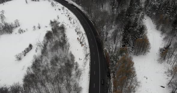 Aerial, tilt up, drone shot, of a wet road, in Romanian highlands, bad weather, on a overcast, winte