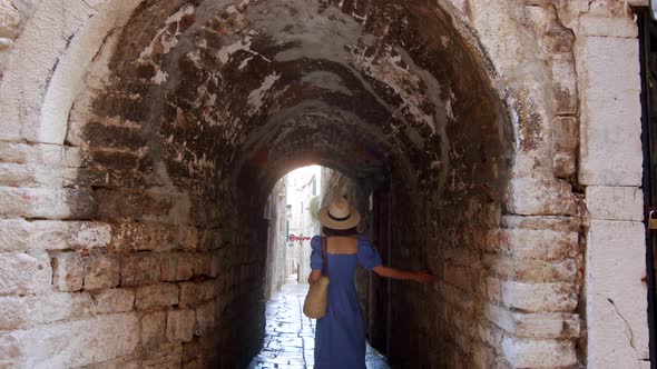 Attractive girl in a blue dress at the arch in the city. Split, Croatia