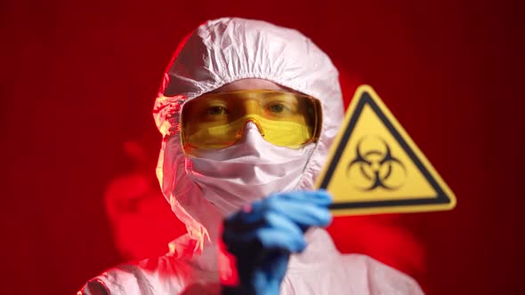 Infectionist Doctor in a Protective Suit Shows a Biohazard Sign