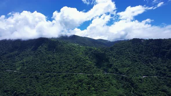 Parallel flight along highway running through dense forest-covered mountain in Eastern Taiwan on a b