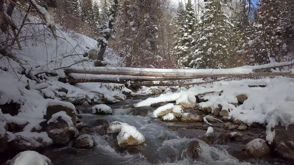 Moving backwards over river in winter landscape viewing upstream